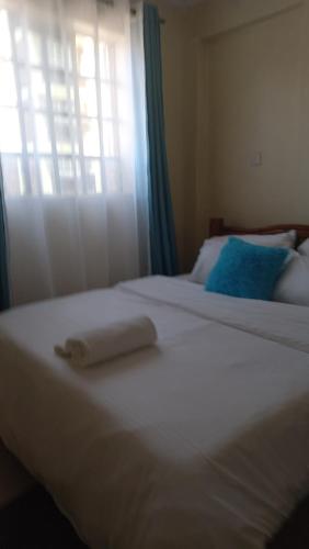 a white bed with a towel on it next to a window at Woodgreek Studio Fully Furnished Apartment in Kisii
