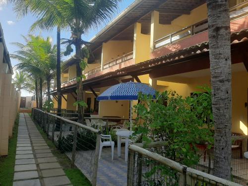 a building with a patio with tables and an umbrella at Village Praia do Flamengo frente mar in Salvador