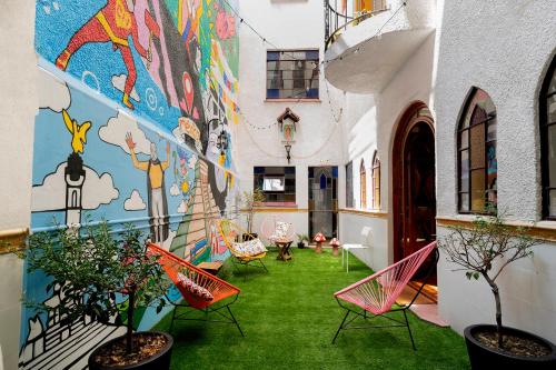 a courtyard with chairs and a mural on the side of a building at Hostal Fungi Casa Rosa in Mexico City