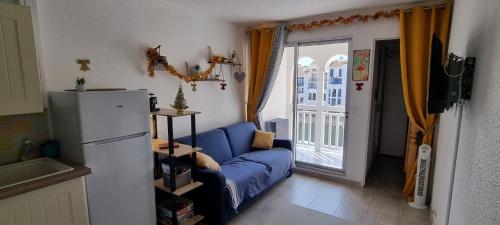 een woonkamer met een blauwe bank en een koelkast bij Résidence Pointe Vermeille - Charmant Studio Cabine avec Jolie vue sur le lac marin in Le Barcarès