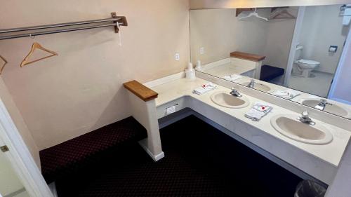 Rodeway Inn - Santa Fe Inn في وينيموكا: حمام به مغسلتين ومرآة كبيرة