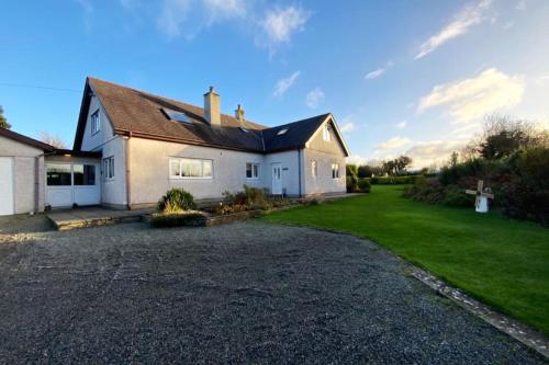 a large white house with a gravel driveway at Jaw-Dropping Beach House In Anglesey in Benllech