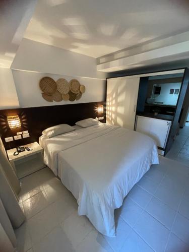 a bedroom with a large white bed and a couch at Pipas Bay - FLAT BEIRA MAR in Pipa