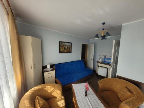 uma sala de estar com um sofá azul e uma mesa em Dom gościnny Monika em Pobierowo