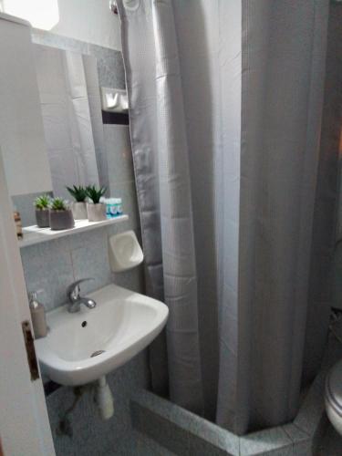 a bathroom with a sink and a shower curtain at George house in Larisa