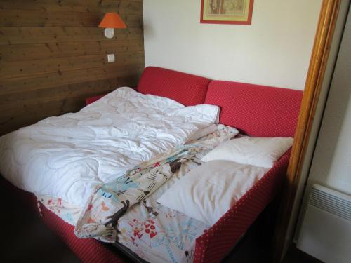 een ongeëvenaard bed in een kamer met een rode bank bij Appartement 644 au pied des pistes de Belle Plagne in La Plagne Tarentaise