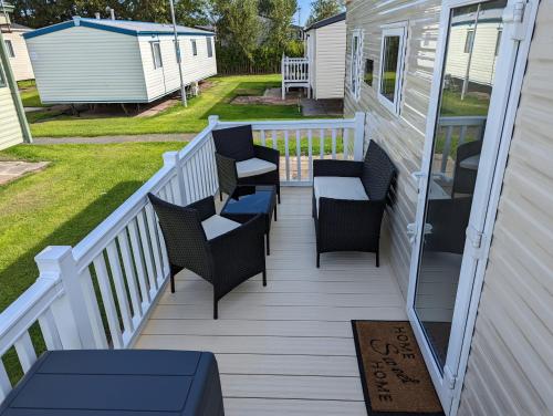 a deck with chairs and a table and a house at The Jones's Family Caravan with private decking - Presthaven in Prestatyn