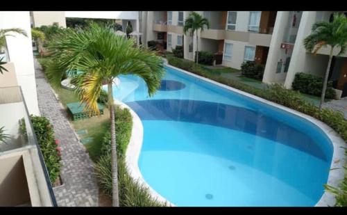 una gran piscina azul junto a un edificio en Guarajuba apartamento máximo 4 pessoas- 2 suítes- 170m praia en Guarajuba