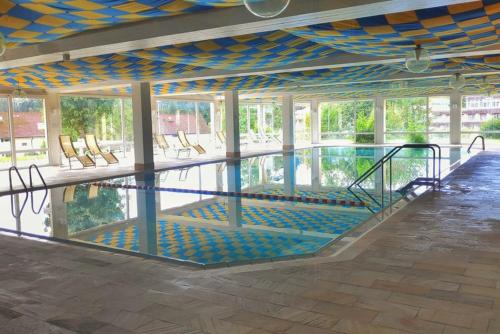 ein großer Pool mit Stühlen in einem Gebäude in der Unterkunft RELAX - GREEN mit Pool und Sauna in Scheidegg