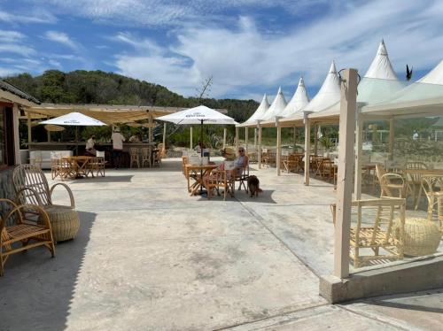 un patio con mesas, sillas y sombrillas blancas en Frontera Sur Apart en Miramar
