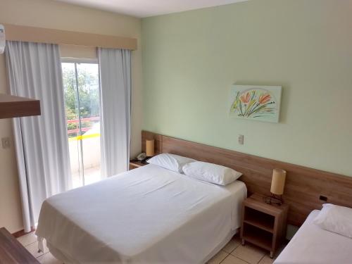 フロリアノポリスにあるIlhamar Canas Hotelのベッド2台と窓が備わるホテルルームです。