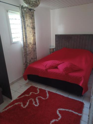 1 dormitorio con cama roja y alfombra roja en Couleurs îsles, en Montjoly