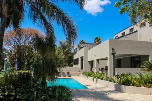 a villa with a swimming pool in front of a house at Fair Glen in Kyalami