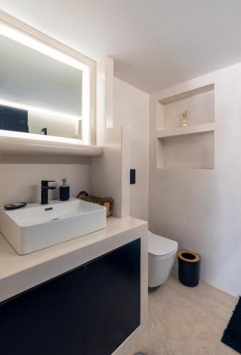 a bathroom with a white sink and a toilet at Black and White Apartment in Pollonia