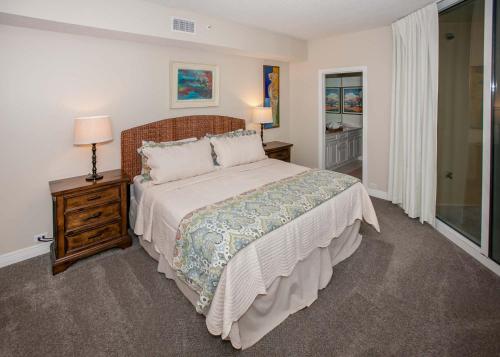 a bedroom with a bed and a night stand with a lamp at Beach Colony East 12C in Pensacola