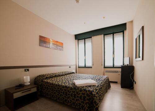 a hotel room with a bed and two windows at Locanda San Fiorenzo in Fiorenzuola dʼArda