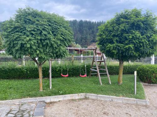 a swing set in a park with two trees at Cosy studios with mountain view near Bansko in Razlog
