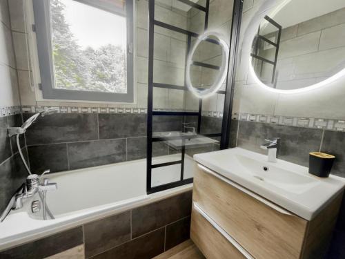 une salle de bain avec une baignoire, un lavabo et un miroir dans l'établissement Studio au centre, 4 pers, proche remontées, balcon ouest, équipements complets - FR-1-572-262, à Arâches-la-Frasse