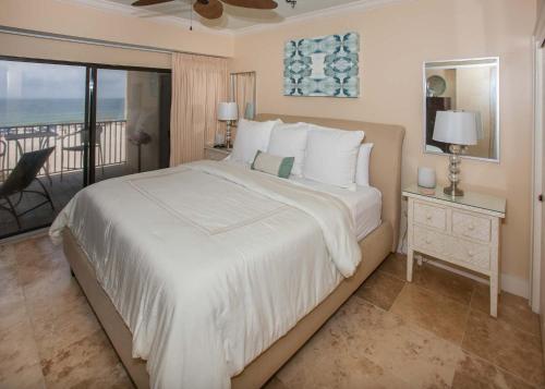a bedroom with a large white bed and a balcony at The Palms 313A in Orange Beach