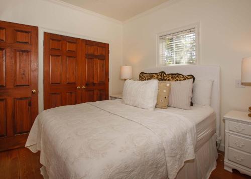 a white bedroom with a bed and a window at Porch Lane Cottage F in Fairhope