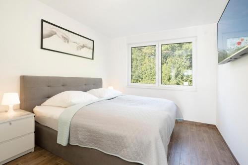 een witte slaapkamer met een bed en 2 ramen bij Baltic Seaside in Sierksdorf