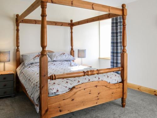 a wooden bed with a wooden frame in a bedroom at West Lanegate Farmhouse in Amisfield Town