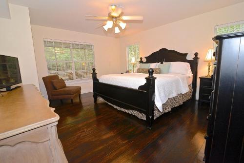 a bedroom with a bed and a chair and a fan at Porch Lane Cottage C in Fairhope