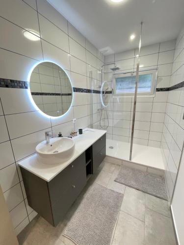 y baño con lavabo, espejo y ducha. en Le Domaine Des Yèbles - Appartement Calme et élégant, en Avon