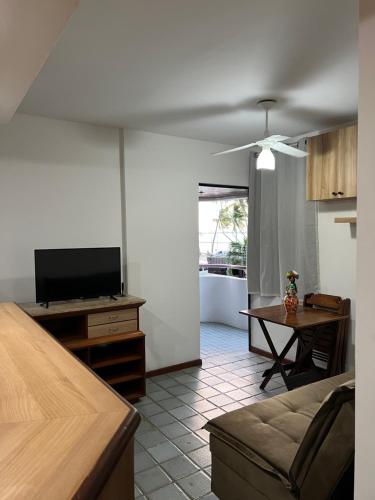 un salon avec un canapé, une télévision et une table dans l'établissement Apartamento Beira Mar - Maceió, à Maceió