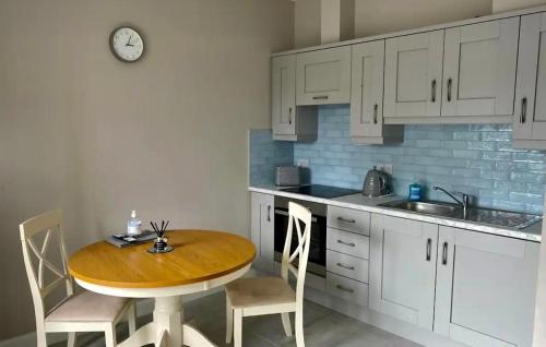 una cucina con tavolo, sedie e orologio di Erne Getaway No.5 Brand new 1 bed apartment a Enniskillen