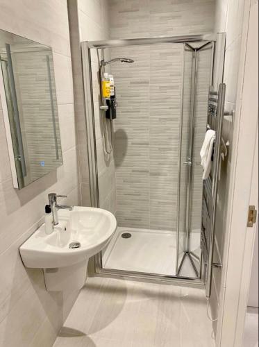 baño blanco con ducha y lavamanos en Erne Getaway No.5 Brand new 1 bed apartment, en Enniskillen