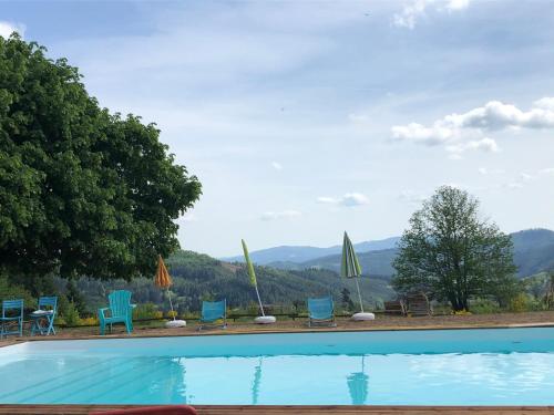 une piscine avec chaises et parasols dans l'établissement LE CHALET de la goutte, à Saint-Appolinaire