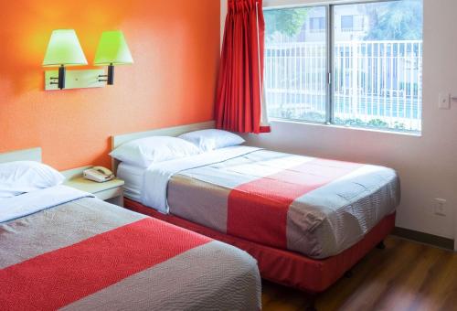 two beds in a room with orange walls and a window at Motel 6-Porterville, CA in Porterville