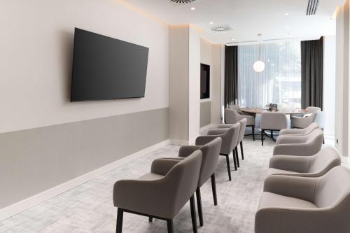a waiting room with chairs and a tv on a wall at Radisson Blu Hotel, Cluj in Cluj-Napoca