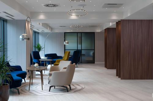 - un hall doté d'une salle d'attente avec des chaises et des tables dans l'établissement Radisson Blu Hotel, Cluj, à Cluj-Napoca