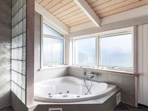 uma banheira na casa de banho com 2 janelas em 8 person holiday home in Otterup em Otterup