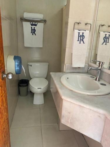 a bathroom with a toilet and a sink with towels at Hotel Real de La Barca in La Barca