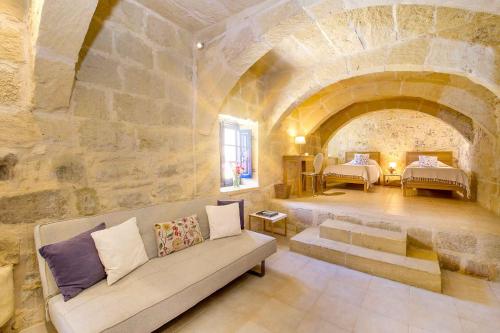 a living room with a couch and a stone wall at Dar Il-Bahar Holiday home in San Lawrenz