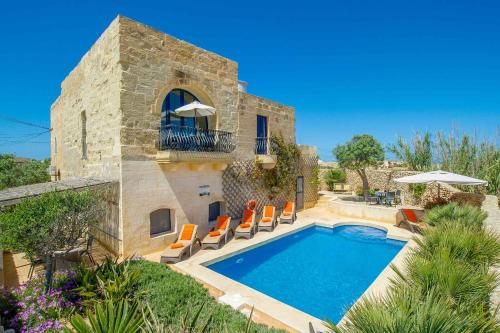 a villa with a swimming pool and orange chairs at Dar Il-Bahar Holiday home in San Lawrenz