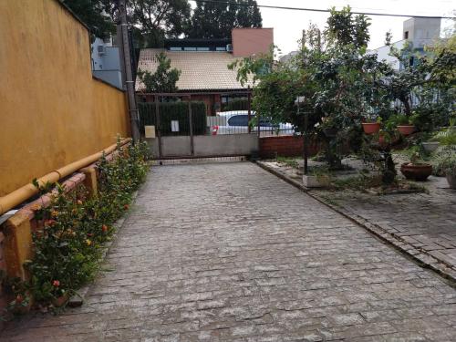 a brick road with flowers and a fence at Casa espaçosa 3 dorms no Centro de Bombinhas in Bombinhas