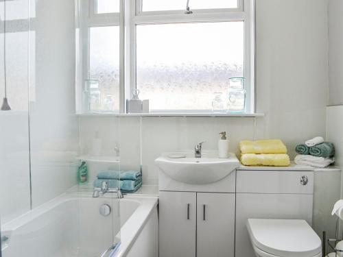 a white bathroom with a sink and a toilet and a window at The Bungalow in Carnoustie