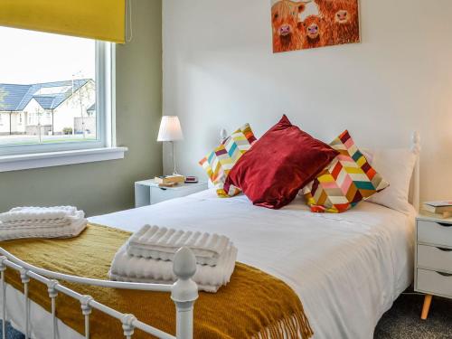 - une chambre avec un grand lit blanc et des oreillers rouges dans l'établissement The Bungalow, à Carnoustie