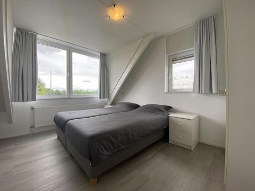 een slaapkamer met een bed en 2 ramen bij Villa Christina in Stevensweert