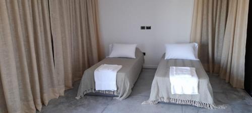 two beds in a room with curtains at Flamencos Rosados in José Ignacio