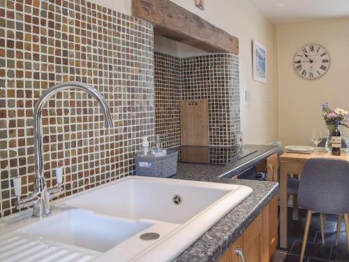 a kitchen with a sink and a counter with a clock at Guildford Bridge Cottage in Llangwm
