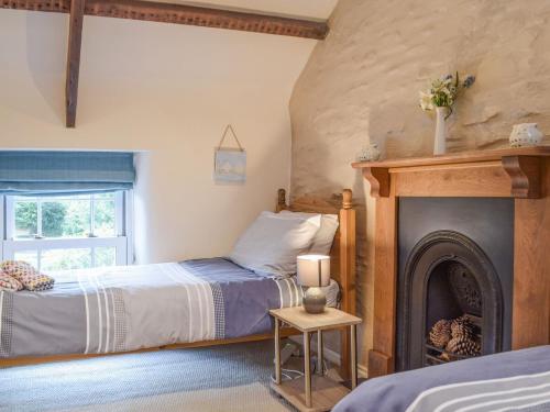 a bedroom with two beds and a fireplace at Guildford Bridge Cottage in Llangwm