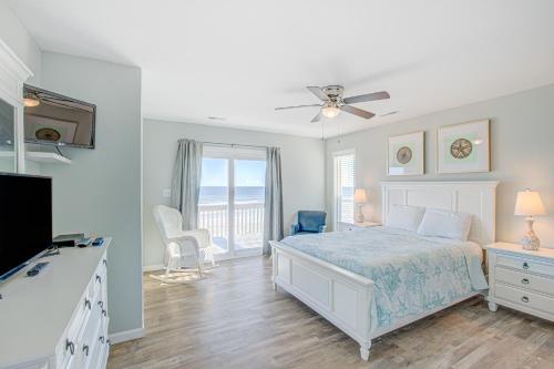 a white bedroom with a bed and a balcony at Avalon Topsail Beach in Topsail Beach