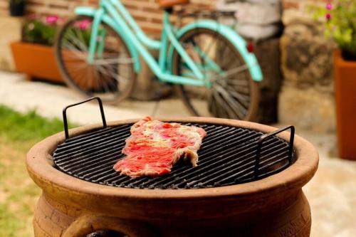 a piece of meat cooking on a grill with a bike at Rustic Luxury Retreat Near Historic Zacatlan in Zacatlán