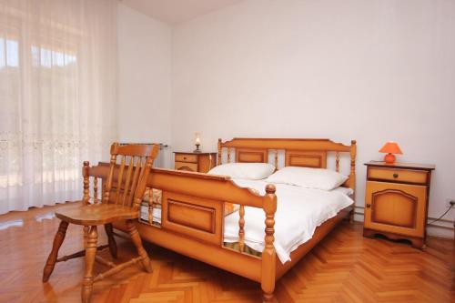 ein Schlafzimmer mit einem Holzbett und einem Holzstuhl in der Unterkunft Apartments by the sea Zaglav, Dugi otok - 8146 in Zaglav