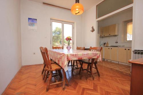 einen Esstisch mit Stühlen und eine Vase mit Blumen darauf in der Unterkunft Apartments by the sea Zaglav, Dugi otok - 8146 in Zaglav